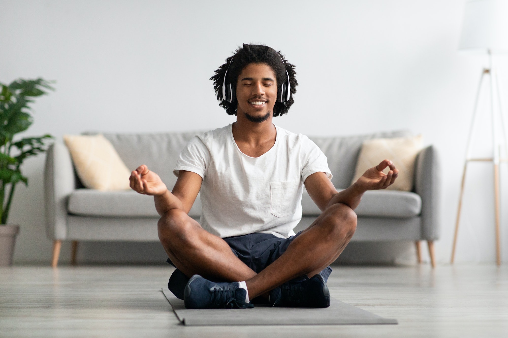 Meditation Concept. Calm Black Guy In Wireless Headphone Meditating At Home